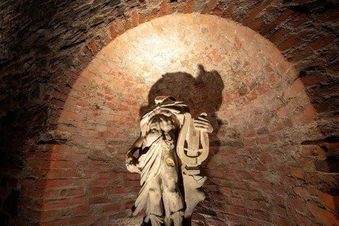 Statue of Apollo in a niche with dramatic shadows, historic city wall in the garden of the