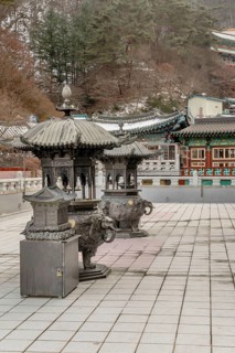 Two ornate metal incense candle burners on patio of Guinsa temple building in South Korea