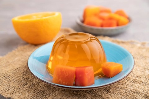 Papaya and orange jelly on gray concrete background and linen textile. side view, close up,