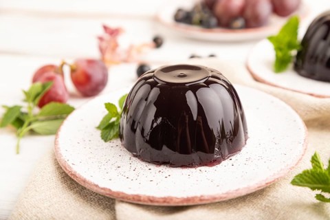 Black currant and grapes jelly on white wooden background and linen textile. side view, close up,