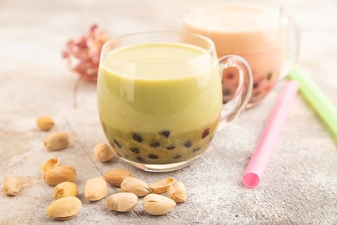 Bubble tea with pistachio and caramel in glass on brown concrete background. Healthy drink concept.