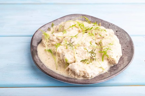 Stewed chicken fillets with coconut milk sauce and mizuna cabbage microgreen on blue wooden