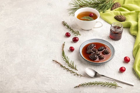 Pine cone jam with herbal tea on gray concrete background and green linen textile. Side view, copy