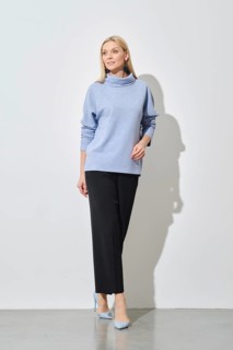 A modern fashion model poses in a relaxed stance, wearing a stylish blue sweater paired with