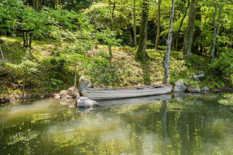 Wooden row boat in water at river bank in Shukkeien gardens in Hiroshima, Japan, Asia