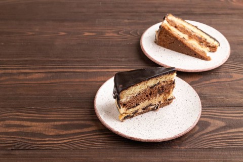 Chocolate biscuit cake with caramel cream on brown wooden background. side view, copy space