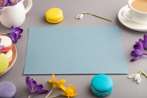 Blue paper sheet mockup with spring snowdrop crocus flowers and multicolored macaroons on gray