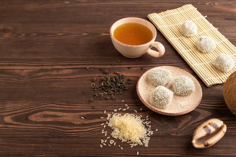 Japanese rice sweet buns mochi filled with pandan and coconut jam and cup of green tea on brown