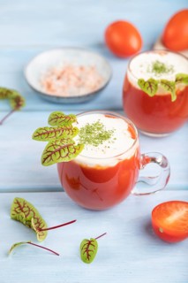 Tomato juice with sorrel, himalayan salt and sour cream in glass on blue wooden background with