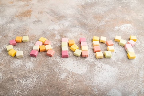 The inscription candy laid out with various fruit jelly chewing candies on brown concrete