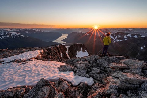 View of mountains and fjord Faleidfjorden, sun star at sunset, mountaineer at the summit of Skala,