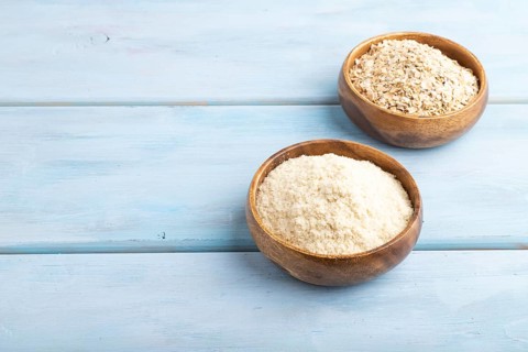 Powdered milk and oatmeal baby food mix, infant formula on blue wooden background. Side view, copy