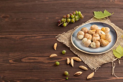 Grape (Burgundy) snails with butter and cheese on brown wooden background and linen textile. Side