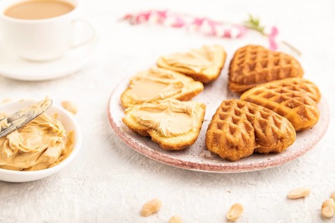 Homemade waffle with peanut butter and cup of coffee on a gray concrete background. side view,