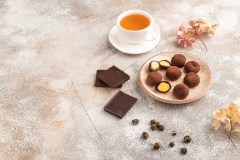 Japanese rice sweet buns chocolate mochi filled with cream and cup of green tea on brown concrete