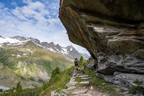 Mountaineer on a hiking trail under a rocky outcrop in a picturesque mountain landscape, Berliner