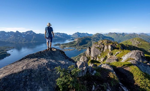 Mountaineer on the summit of Dronningsvarden or Stortinden, mountains and fjord Raftsund,
