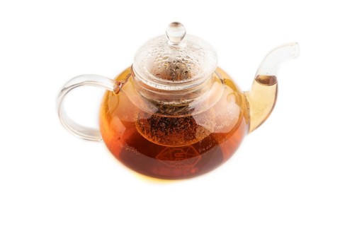 Red tea with herbs in glass teapot isolated on white background. Healthy drink concept. Side view,