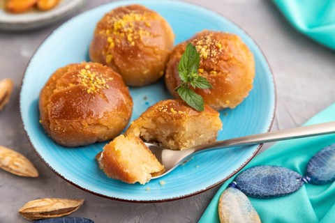 Homemade traditional turkish dessert sekerpare with almonds and honey, cup of green tea on gray