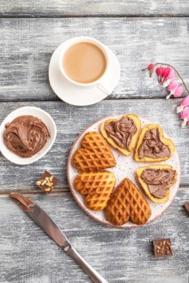 Homemade waffle with chocolate butter and cup of coffee on a gray wooden background. top view, flat