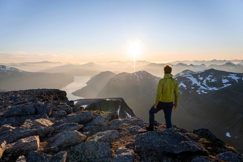 View of mountains and fjord Faleidfjorden, sun star at sunset, mountaineer at the summit of Skala,