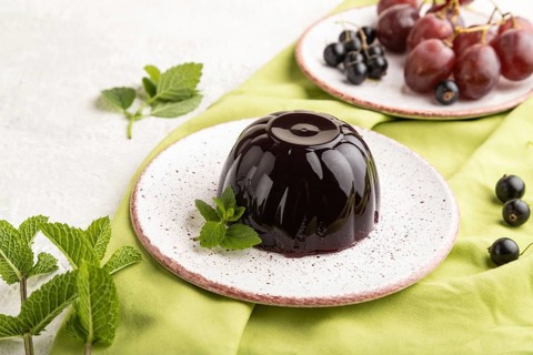 Black currant and grapes jelly on gray concrete background and green linen textile. side view,