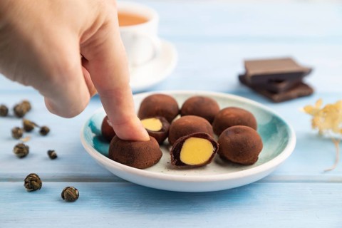 Japanese rice sweet buns chocolate mochi filled with cream and cup of green tea with hand on blue