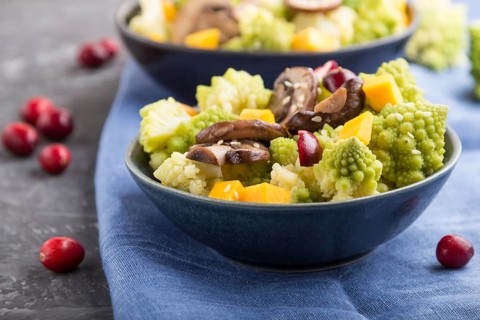 Vegetarian salad from romanesco cabbage, champignons, cranberry, avocado and pumpkin on a black