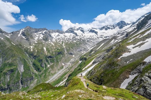 Mountaineer on hiking trail in picturesque mountain landscape, in the background mountain peak