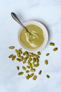 Pistachio cream in small bowls with spoon, pistachios