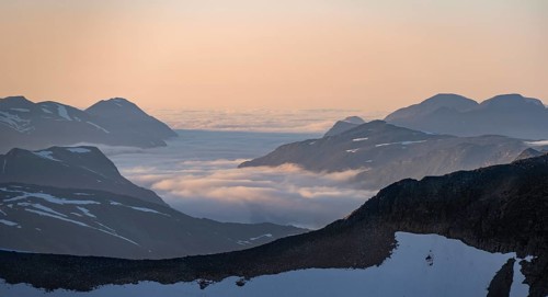 Mountain panorama with clouds in the valley, mountain peaks in soft light at sunset, view from the