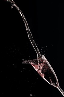 Rose champagne pours in an arc into a champagne glass on a black background