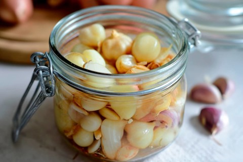 An open preserving jar full of pickled shallots and garlic cloves on a table, AI generated, AI