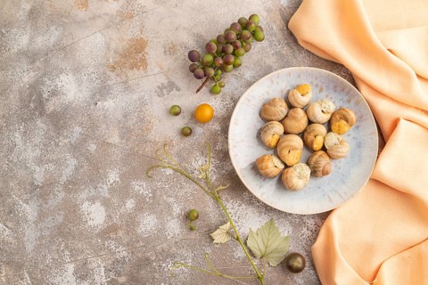 Grape (Burgundy) snails with butter and cheese on brown concrete background and orange textile. Top