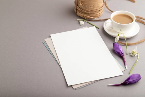 White paper sheet mockup with spring snowdrop crocus and galanthus flowers and cup of coffee on