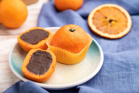 Truffle chocolate tangerine candies on a white wooden background and blue linen textile. Side view,