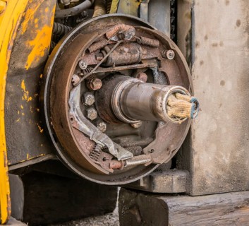 Closeup view of exposed rusty break shoe assembly and axle with dirty white cloth stuffed into open