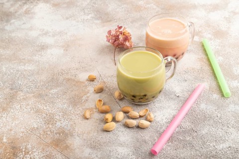 Bubble tea with pistachio and caramel in glass on brown concrete background. Healthy drink concept.