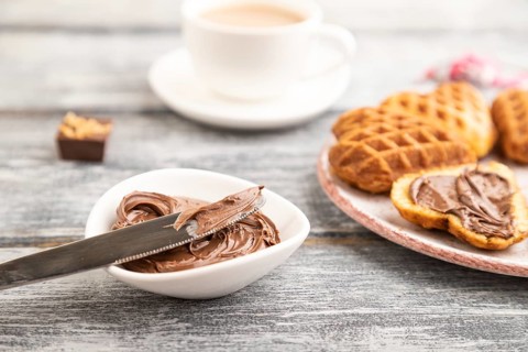 Homemade waffle with chocolate butter and cup of coffee on a gray wooden background. side view,