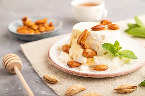 Ricotta cheese with honey and almonds on gray concrete background and linen textile. side view,