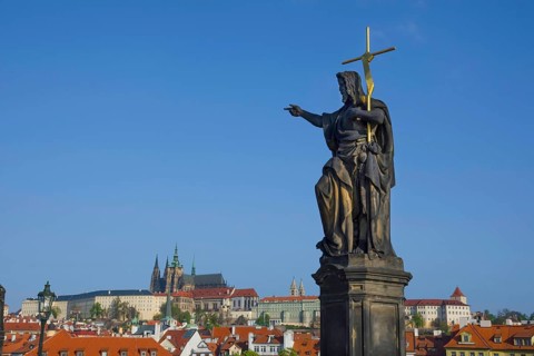 Statue of St. John the Baptist on Charles Bridge, with Hradcany castle and St. Vitus Cathedral in