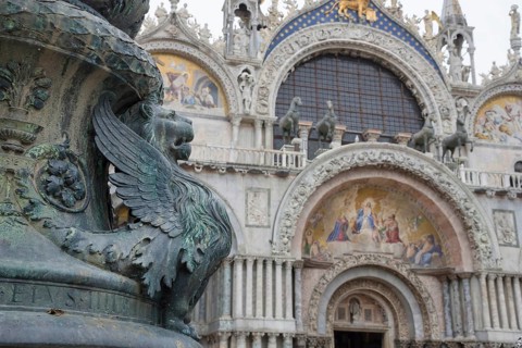 Old street ornament with winged lions and San Marco Basilica in the background, in St. Mark Square,