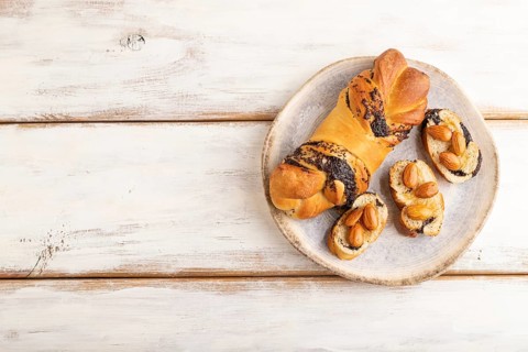 Homemade sweet bun with honey almonds on a white wooden background. top view, flat lay, copy space