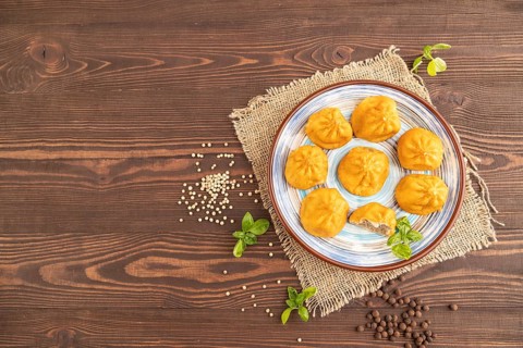 Fried manti dumplings with pepper, basil on brown wooden background and linen textile. Top view,