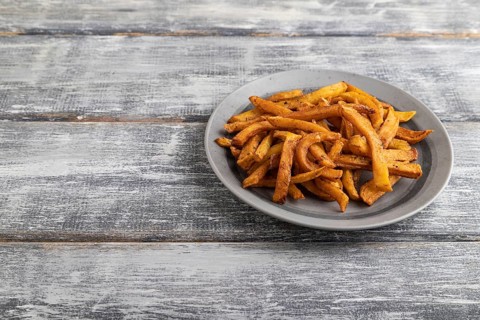 Heap of fried potato on a gray plate on a gray wooden background. Side view, close up, copy space