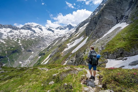 Mountaineer on hiking trail in picturesque mountain landscape, in the background mountain peak