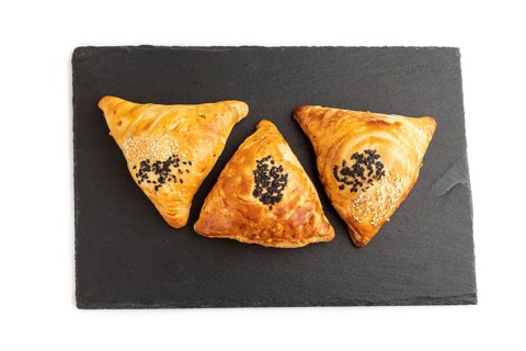 Homemade asian pastry samosa on black slate board isolated on white background. top view, flat lay,