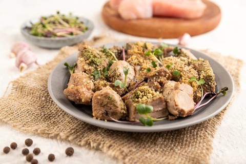 Stewed turkey fillet with garlic and sprouts of radish on white wooden background and linen textile