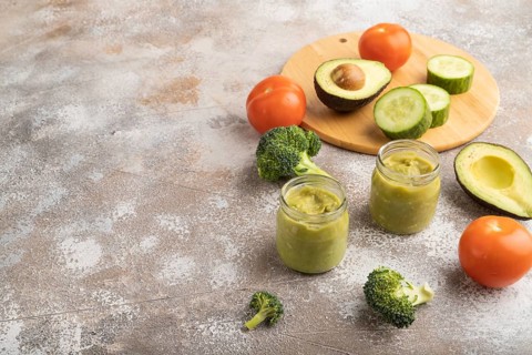 Baby puree with vegetable mix, broccoli, tomatoes, cucumber, avocado infant formula in glass jar on