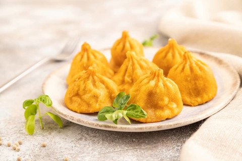 Fried manti dumplings with pepper, basil on gray concrete background and linen textile. Side view,
